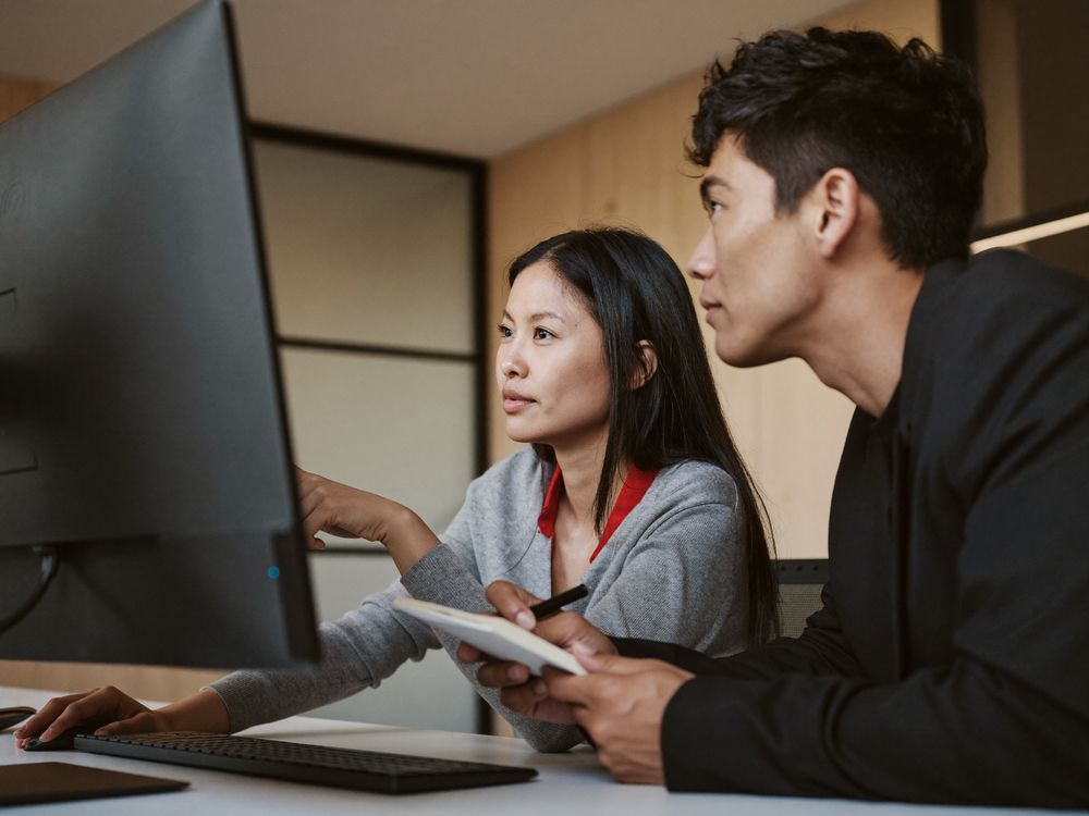 Two Vexabit team members reviewing delivery work together on a large monitor