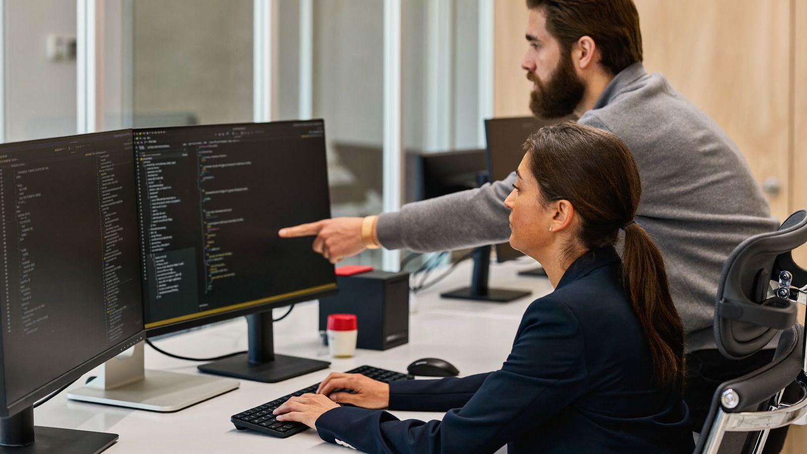 Two Vexabit engineers pair programming at a dual-monitor workstation